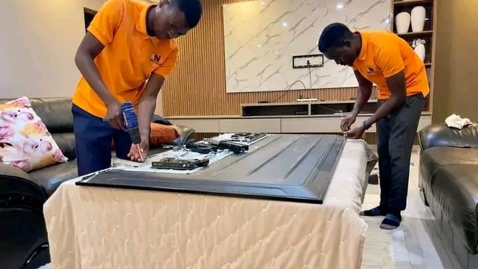 Bluetech TV Repairs technicians dismantling and repairing a large flat-screen TV in a customer's home